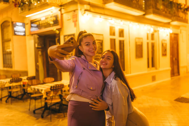 istock Two young friends taking selfies while outdoors at night 2124795873