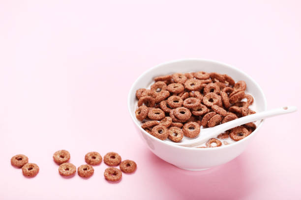 istock Chocolate corn flakes in bowl with milk and spoon on pink background 2124846410