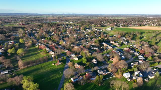 American Community with houses in rural area of American Town. Spring Season with colorful trees and agricultural fields at sunny day. Aerial top down shot.