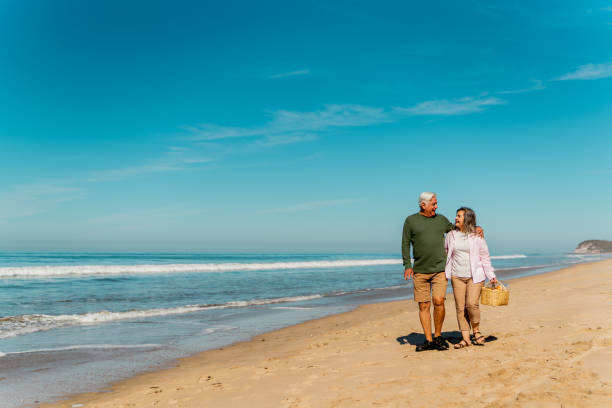 istock Senior couple talking and walking through the beach 2124928516