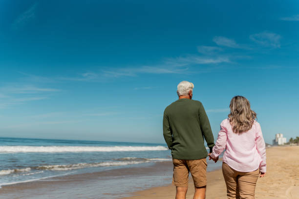 istock Senior couple talking and walking through the beach 2124929559
