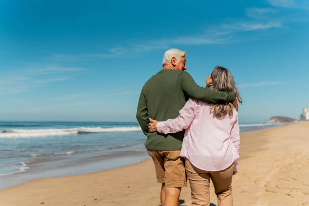 istock Senior couple talking and walking through the beach 2124929560