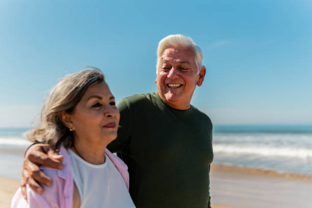 istock Senior couple talking and walking through the beach 2124929564