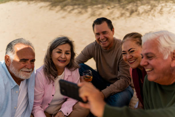 istock Senior friends using mobile phone on the beach 2124939108
