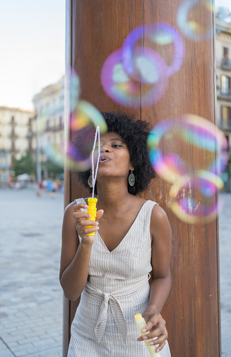 African American woman blowing soap bubbles in the square