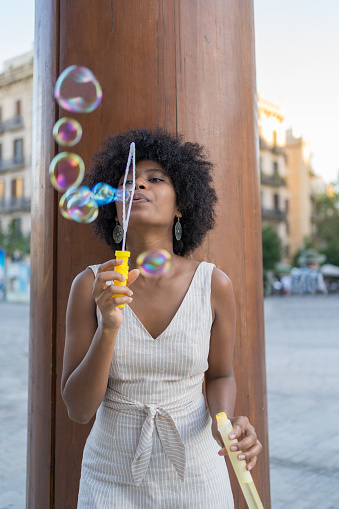 Close-up of a mixed race woman blowing soap bubbles in the square
