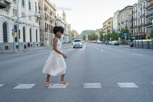 Young Afro-haired woman in a hippie dress crossing the street in fear