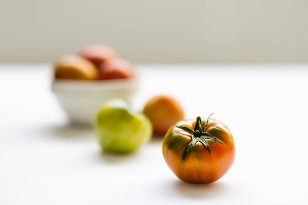 Fresh daejeo tomato in a white bowl under warm sunlight indoor natural light on white background
