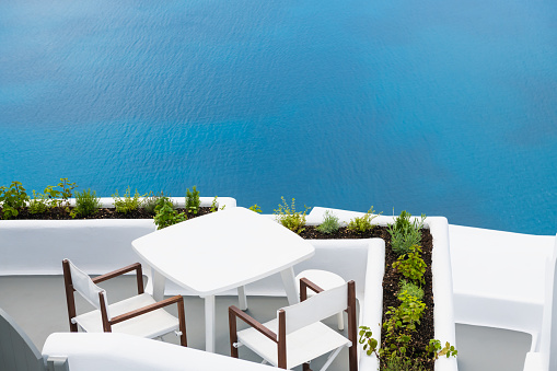White architecture in Santorini island, Greece. Two chairs with table on the terrace with sea view. Travel and summer vacation concept