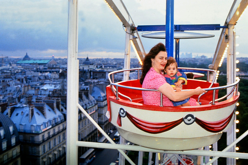 young woman and her daughter in the basket of the Ferris wheel at the funfair in Paris