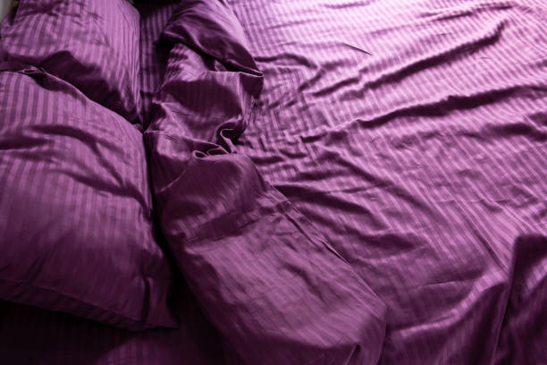 istock morning mess on a crumpled silk bed sheet, lilac color 2124992571