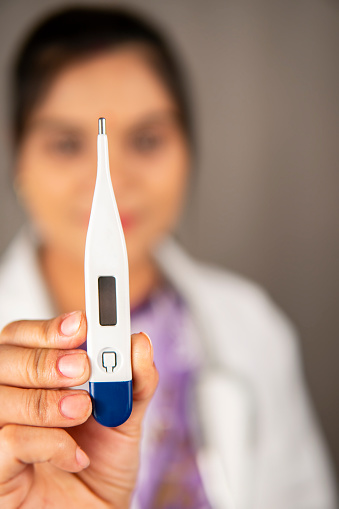 Close up of hand indian female doctor holding a digital thermometer.