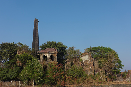 Old, damaged, and abandoned building with a tall brick chimney next to the Sassoon Docks in Mumbai