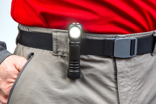 flashlight with clips on the waistband of trekking trousers. EDC items