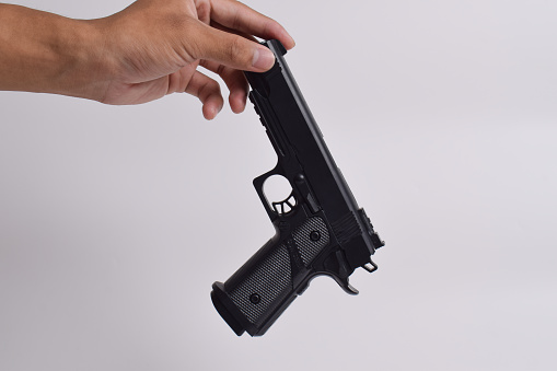 Male hand holding a gun on white background . A Pistol in a man's hand