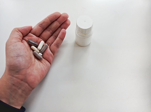 Hand with pill, various medicine