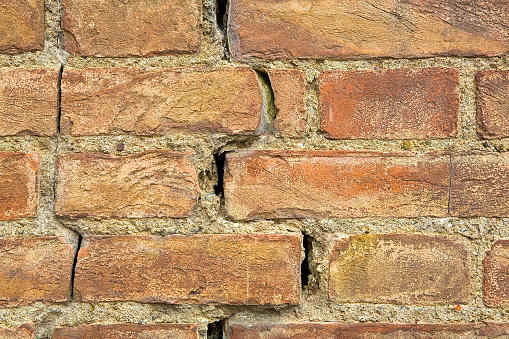 Dangerous old exposed cracked brick wall due to structural foundation failure, soil subsidence, earthquake, corrosion and deterioration of building materials,