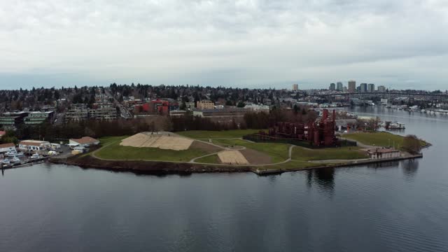 Dolly in aerial drone wide shot of the famous tourist destination Gas Works park in Seattle, Washington located on Lake Union surrounded by boats and homes on a overcast spring evening