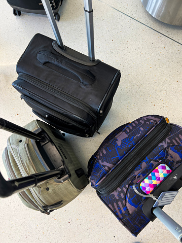 Overhead view of several suitcases with handles raised. The luggage rests on a clean terrazzo floor at an airport gate. Travel, vacation or business travel concept.