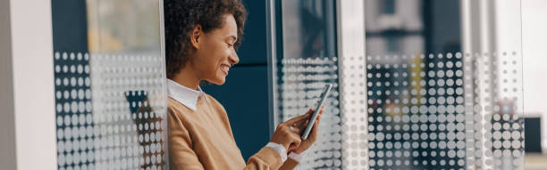 istock Stylish female freelancer is using mobile phone standing in coworking during break time 2125182101