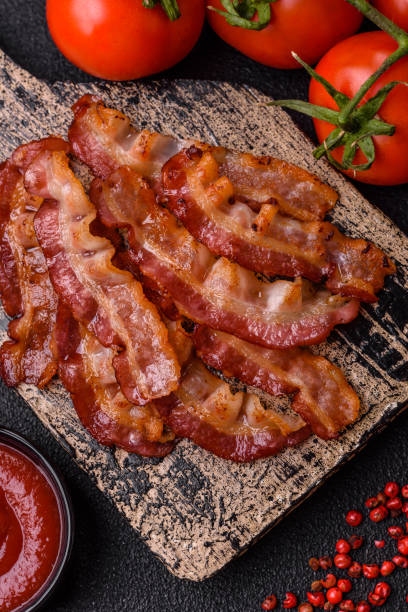 istock Delicious fresh fried bacon with salt and spices on a dark background 2125183167