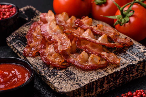 istock Delicious fresh fried bacon with salt and spices on a dark background 2125183317
