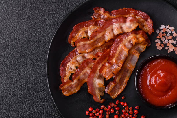 istock Delicious fresh fried bacon with salt and spices on a dark background 2125184261