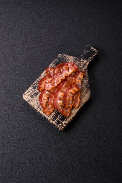 istock Delicious fresh fried bacon with salt and spices on a dark background 2125184767