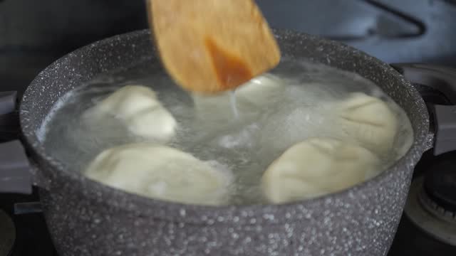 Handmade khinkali in saucepan of boiling water on domestic kitchen