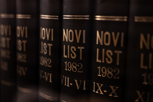 Rijeka, Croatia – March 21, 2023: A row of books with golden old editions of Novi list