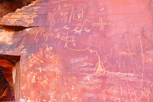 Ancient Native American rock art, damaged by modern graffiti, Valley of Fire, Nevada. Petroglyphs in red rock face