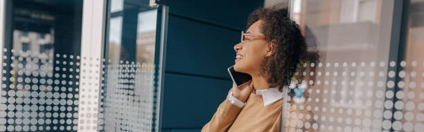istock Stylish female freelancer is talking phone with client while standing on coworking background 2125197233