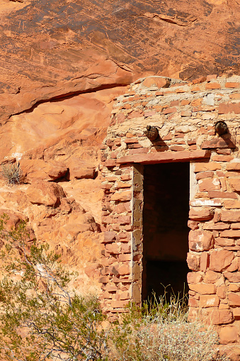 Door to an old sandstone cabin in Valley of Fire State Park, Nevada, USA. On the rock face above the door old native-American petroglyphs.