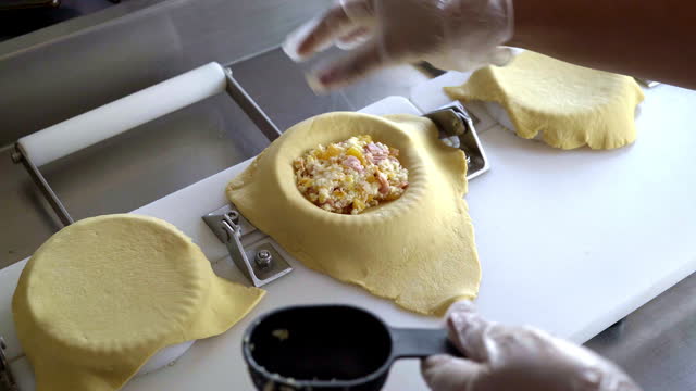 Hands of an operator finishing the process in the preparation of an empanada
