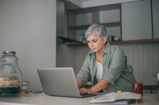 istock Asian Senior woman work from home at kitchen using laptop 2125242726