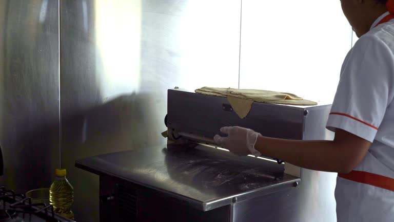 Latin woman is inside the kitchen of a small empanada food business