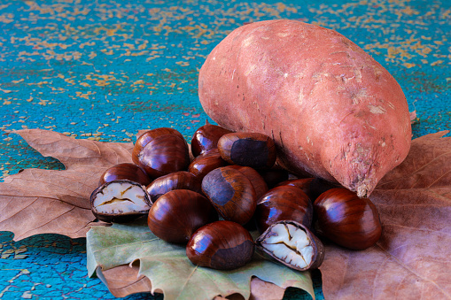 Chestnuts and Sweet Potato on dry leaves creating an autumn atmosphere ready to be roasted