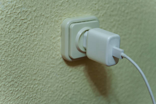 Close-up of a mobile phone charger plugged into the home electrical grid