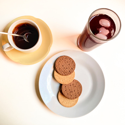 Snack with cookies ,melted chocolate in a cup and tea infusion in a glass with ice . Delicious break at home for a sweet snack