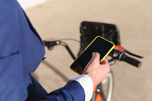 Close up of man hands typing in cellphone and using a bike. High quality photo