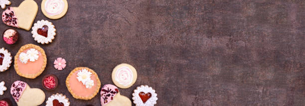 istock Mothers Day or love themed baking corner border with assorted cookies and sweets on a dark stone banner background 2125398664