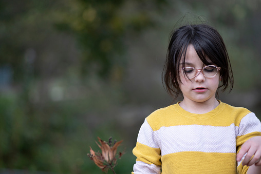 Portrait of a little girl in a yellow sweater and glasses.