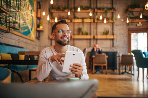 istock Young man enjoying coffee at the cafe and using a digital tablet 2125410507