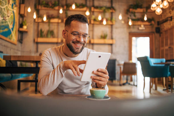 istock Young man enjoying coffee at the cafe and using a digital tablet 2125412560