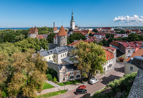 Travel image of old town Tallinn Estonia on a beautiful summer day with blue sky. Aerial view. Historic buildings and church tower in city center.