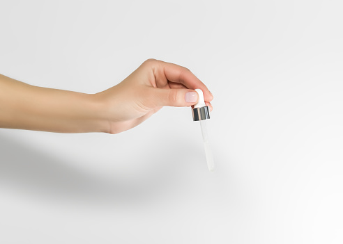 hand holding a pipette with cosmetic serum on a white background