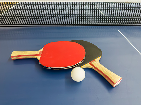 A game of table tennis being played on a blue ping pong table.