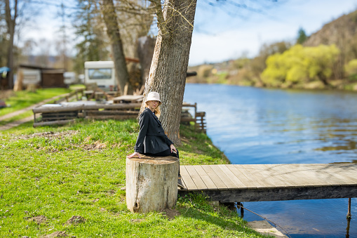 A woman sits on a stump near the Berunka River in early spring in Czech. nature beauty harmony landscape outdoors. High quality photo