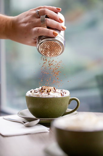 Sprinkling cinnamon on a cafe mocha