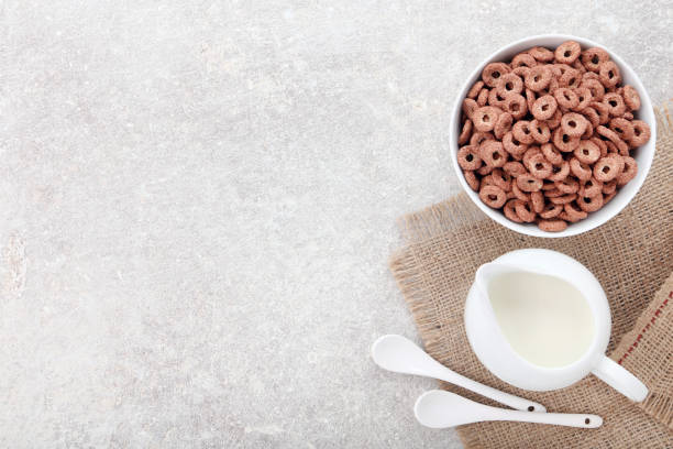 istock Chocolate corn flakes with milk in jar and spoons on grey background 2125680885